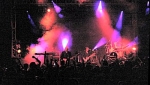 The crowd watch as the band are surrounded by smoke and light