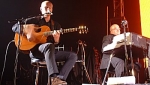 Stu singing with his acoustic guitar and Tim at the Rhodes