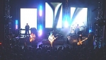 The five band members on stage in front of the video screens